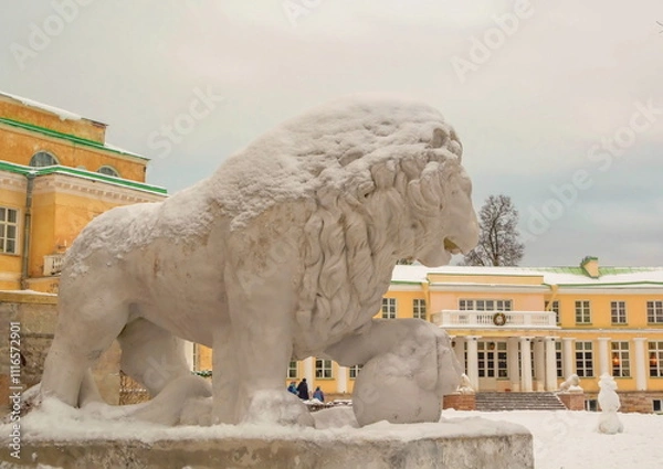 Fototapeta Stone snow-covered sculpture of a lion in an ancient noble manor