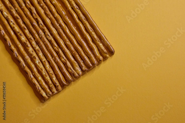 Obraz Deliciously Crispy Pretzel Sticks Set Against a Bright Yellow Background for Visual Appeal