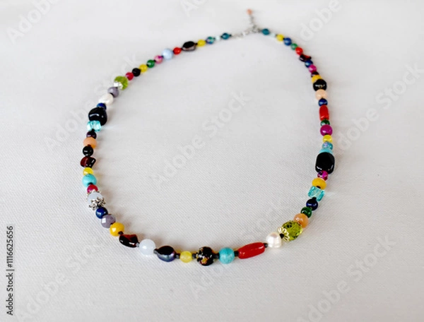 Fototapeta A bohemian style necklace on a whitesurface