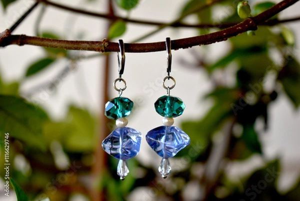 Fototapeta A chic pair of earrings  hanging on a branch.Handmade jewellery.