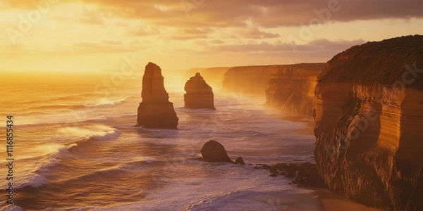 Fototapeta A rugged coastal landscape with towering sea stacks and waves crashing against the rocks. The golden light of sunrise adds warmth to the dramatic scene.