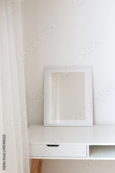 Fototapeta Modern frame on the white table against the wall. Frame mock up, copy space for your text.