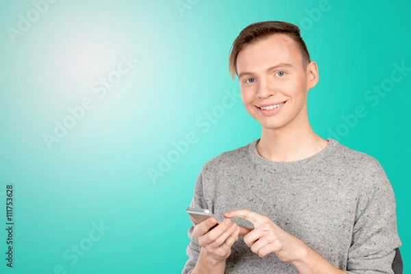 Fototapeta Young man typing text message on his cellphone