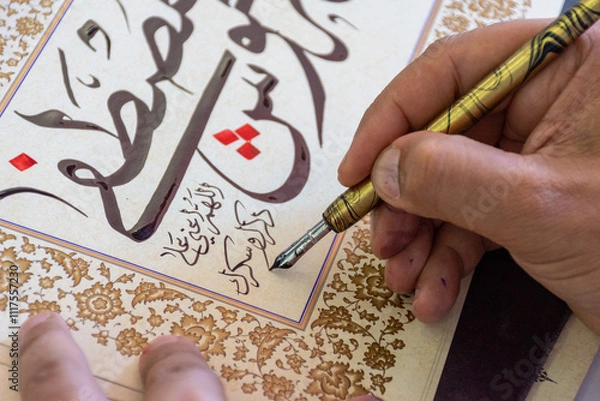Fototapeta Close-up of a calligraphist writing an Arabic name for a customer in Arabic calligraphy with ink.