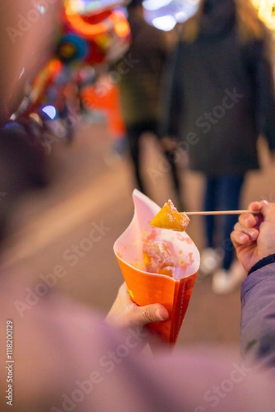 Obraz Fresh doughnuts with icing sugar at the Christmas market are eaten by a child.