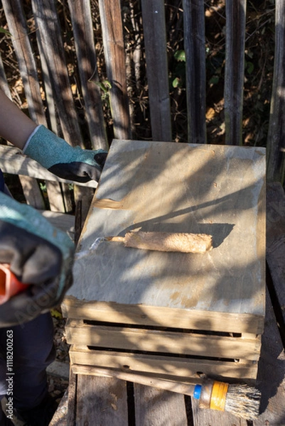 Obraz a child paints a wooden box with brushes in the garden