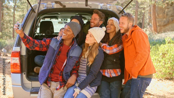 Fototapeta Group Of Friends Outdoors Posing For Selfie Sitting In Open Tailgate Of Car Before Autumn Walk 