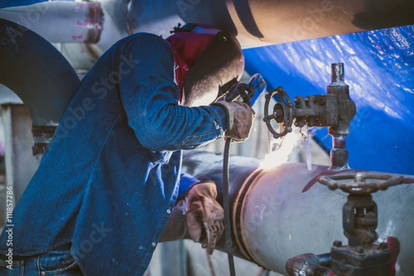 Obraz Welder is welding pipe on construction site