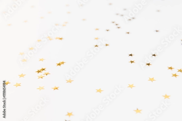 Fototapeta Gold sparkle confetti stars on a white background. Glitter, shine, bright. Christmas festive flat lay, winter holiday, new year, happy birthday concept. Banner for greeting card, top view, copy space.
