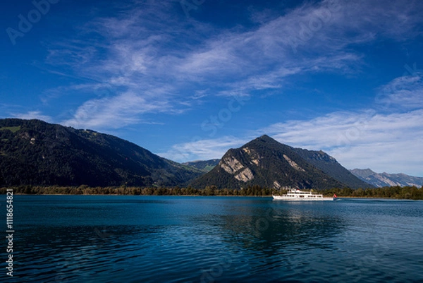 Fototapeta lake thun with surrounding hills in bernese oberland switzerland with boat during summer with blue cloudy sky