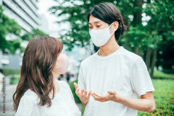 Fototapeta マスクをして何かを話す若いカップル
