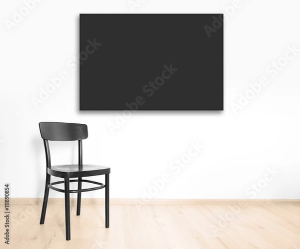 Fototapeta Black chair and empty picture frame on wall background