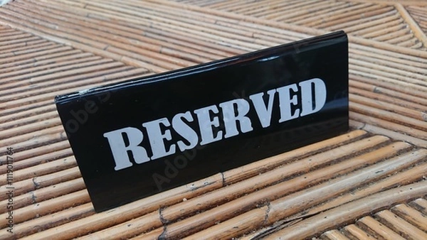 Fototapeta Reserved Sign, black acrylic at bamboo table white text