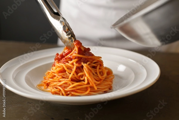 Fototapeta レストランのトマトソースのパスタを盛り付けるシェフ