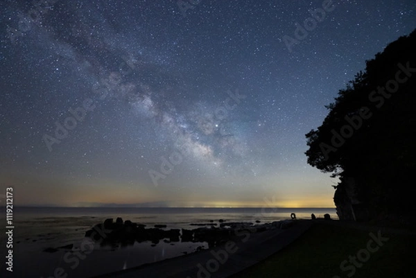 Fototapeta 能登半島にある海辺の丘と天の川と輝く星々