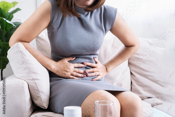 Fototapeta Asian woman suffering from stomach pain due to gastritis and irritable bowel syndrome