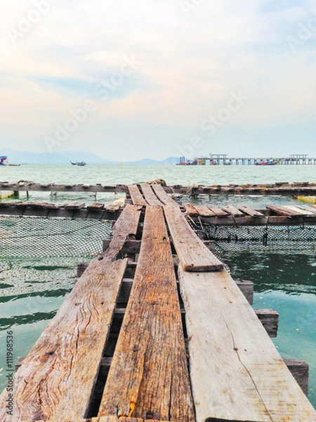 Obraz A wooden fishing bridge floating on the sea in Phuket , Thailand, with partly cloud sky and pier as a background.
