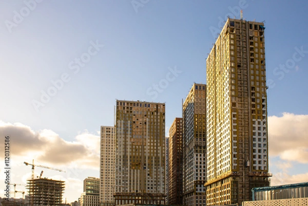 Fototapeta Construction of a multi-story residential building. Construction site. Construction of skyscrapers. Tower crane on formwork on residential buildings. Built housing.