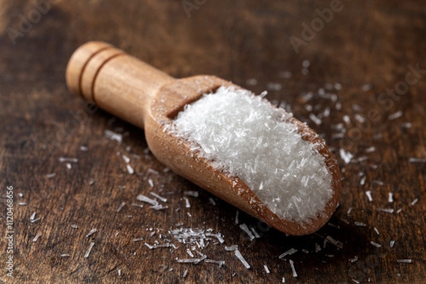 Obraz MSG white crystals n a wooden scoop macro. Scoop full of monosodium glutamate over brown wooden background. E621 flavor enhancer food additive concept.
