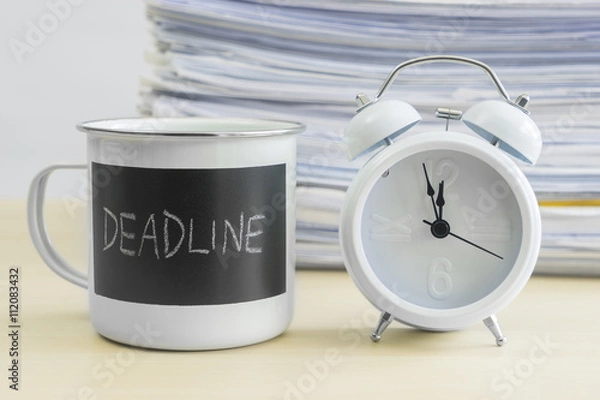 Fototapeta Deadline words on mug with clock and stack of papers