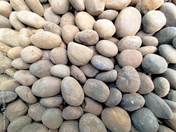 Fototapeta Smooth stone wall background with pebbles on the beach and a textured rocky surface