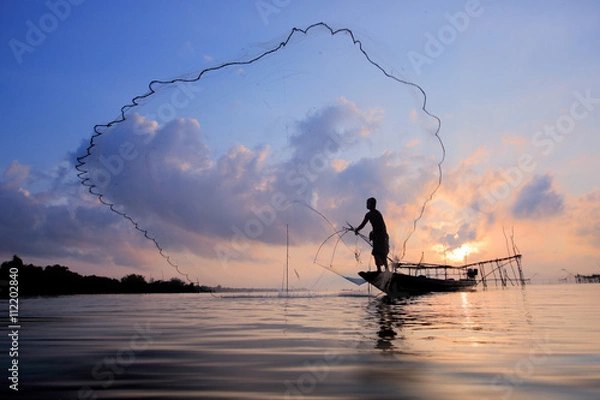 Fototapeta Fishermen on boat fishing with a fishnet,the old traditional equipment of Thai fishery.Silhouette scene in Pak Pra Village, Pattalung province, Thailand.