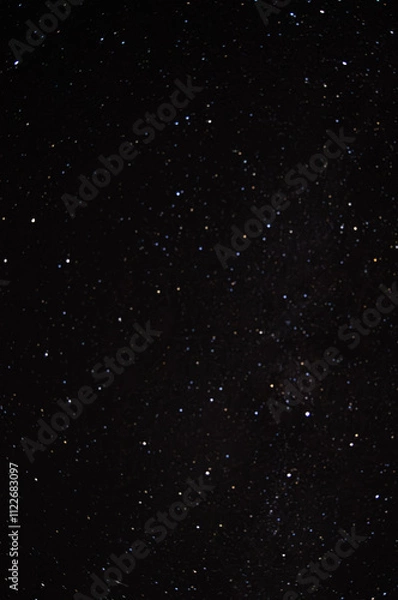 Fototapeta Wide expanse of a starry night sky with an array of bright and dim stars scattered across a deep black background, creating a cosmic view.