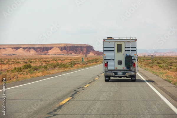 Fototapeta Camper Van, RV, on a US-American Highway  surrounded by Desert an Mountains, Landscape, Copy Space