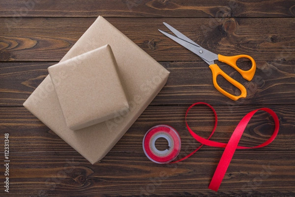 Fototapeta Gift box with red ribbon and scissors on wooden table