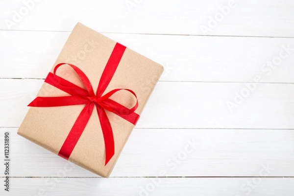 Fototapeta Gift box with red ribbon bow on white wooden background