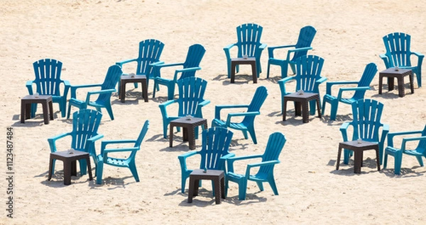 Fototapeta Outdoor seating area on the beach with black and blue plastic chairs and tables.