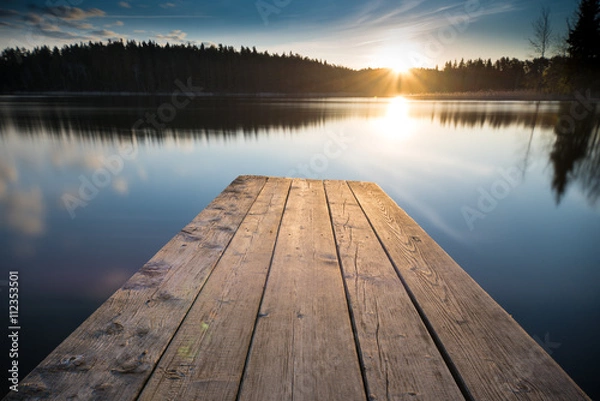 Fototapeta sunset on the lake. Old wooden pier into the horizon and sun lights. Beginning on a new day