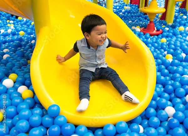 Fototapeta Boy playing slider in the playground balls pool