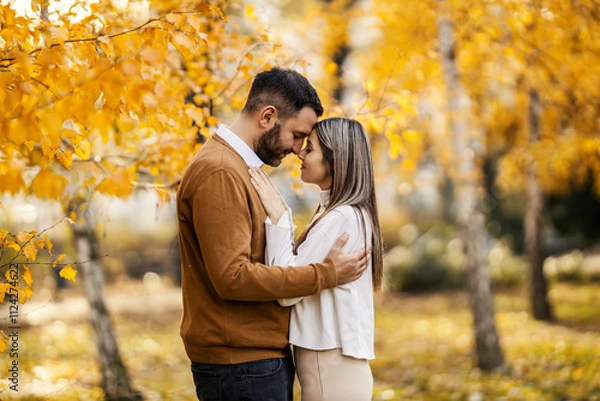Obraz Side view of young couple cuddling and hugging in city park face to face.