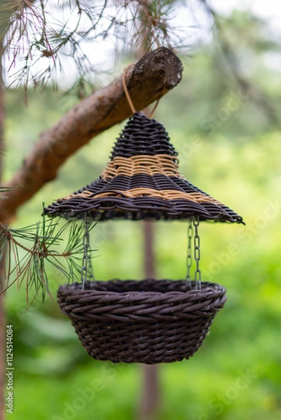 Fototapeta wicker bird feeder in the forest (blurred background, shallow depth of field)