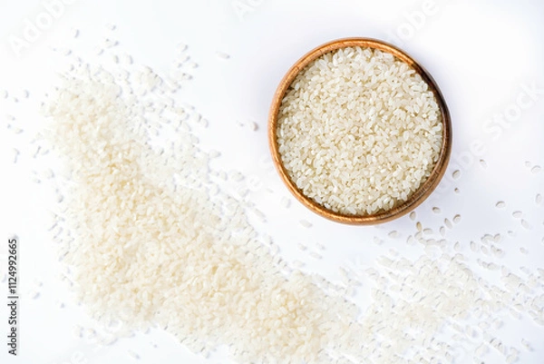 Fototapeta Wooden bowl with rice on white background with scattered grain. Healthy nutrition and light breakfast.