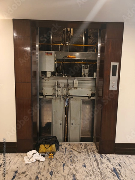 Fototapeta Maintenance crew is working on an elevator system in a hotel corridor with tools and equipment nearby