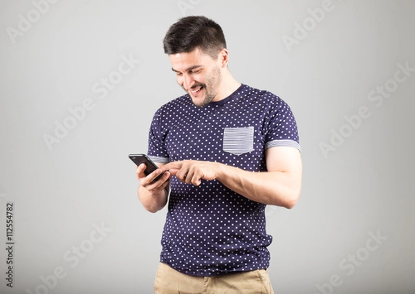 Fototapeta Young man using his smartphone
