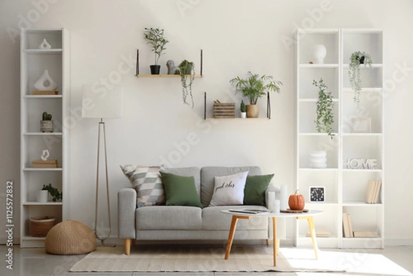 Fototapeta Cozy sofa, coffee table, shelving units and floor lamp in interior of living room