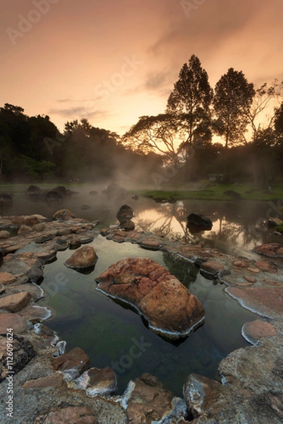 Fototapeta Hot springs over rock terrain with misty and morning sunrise rays and Natural Mineral Water of Chae Son National Park in Lampang Province, Thailand.