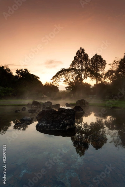 Fototapeta Hot springs over rock terrain with misty and morning sunrise rays and Natural Mineral Water of Chae Son National Park in Lampang Province, Thailand.