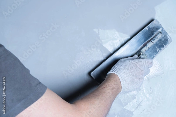 Obraz Using a trowel, a person applies epoxy adhesive to repair a wall surface effectively.