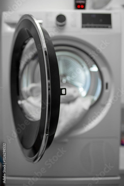 Fototapeta View of the tumble dryer or dryer machine with the door open and a towel inside