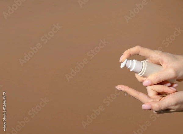Obraz Banner Female hand holds a bottle with dispenser with cosmetic serum. Natural cosmetic product for skin purity and hydration. Unmarked bottle with product for face skin care.