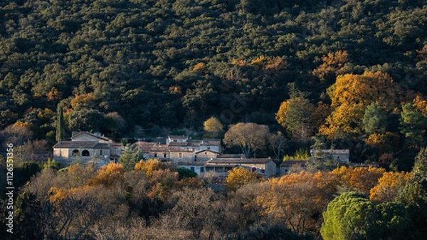 Fototapeta Village typique en pierre sèche du Sud de la France niché au coeur d'une forêt à flanc de colline dans le soleil d'un soir d'automne.