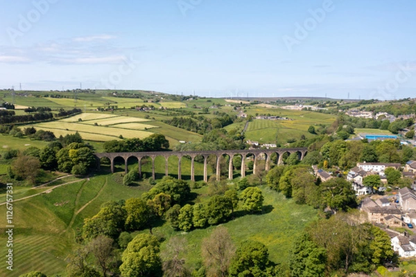 Fototapeta Aerial drone photo of the town of Thornton which is a village within the metropolitan borough City of Bradford in West Yorkshire, England showing the village and famous viaduct in the summer time.