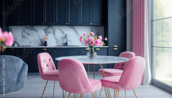 Fototapeta A stylish dining area with a round marble table and pink velvet chairs, set against a backdrop of dark blue cabinetry and a marble countertop.
