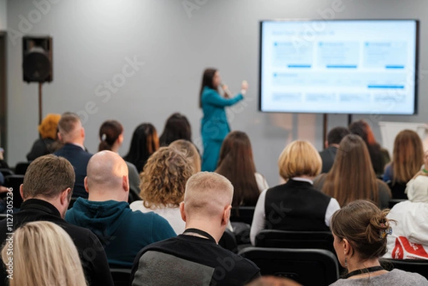 Obraz Audience engaged during a presentation with speaker using a microphone and a screen.