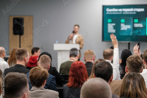 Obraz Focused audience listens to speaker during seminar. Interactive discussion and participation evident.