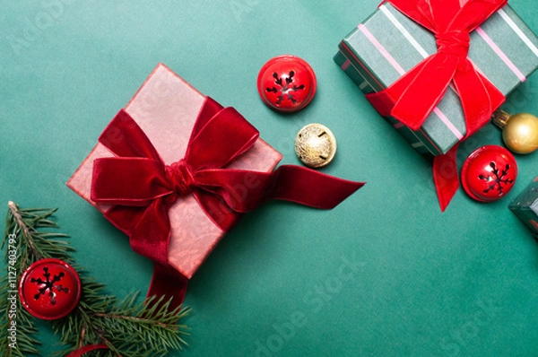 Fototapeta Beautiful Christmas background flat lay with gifts on green with red  ribbons and pine branches